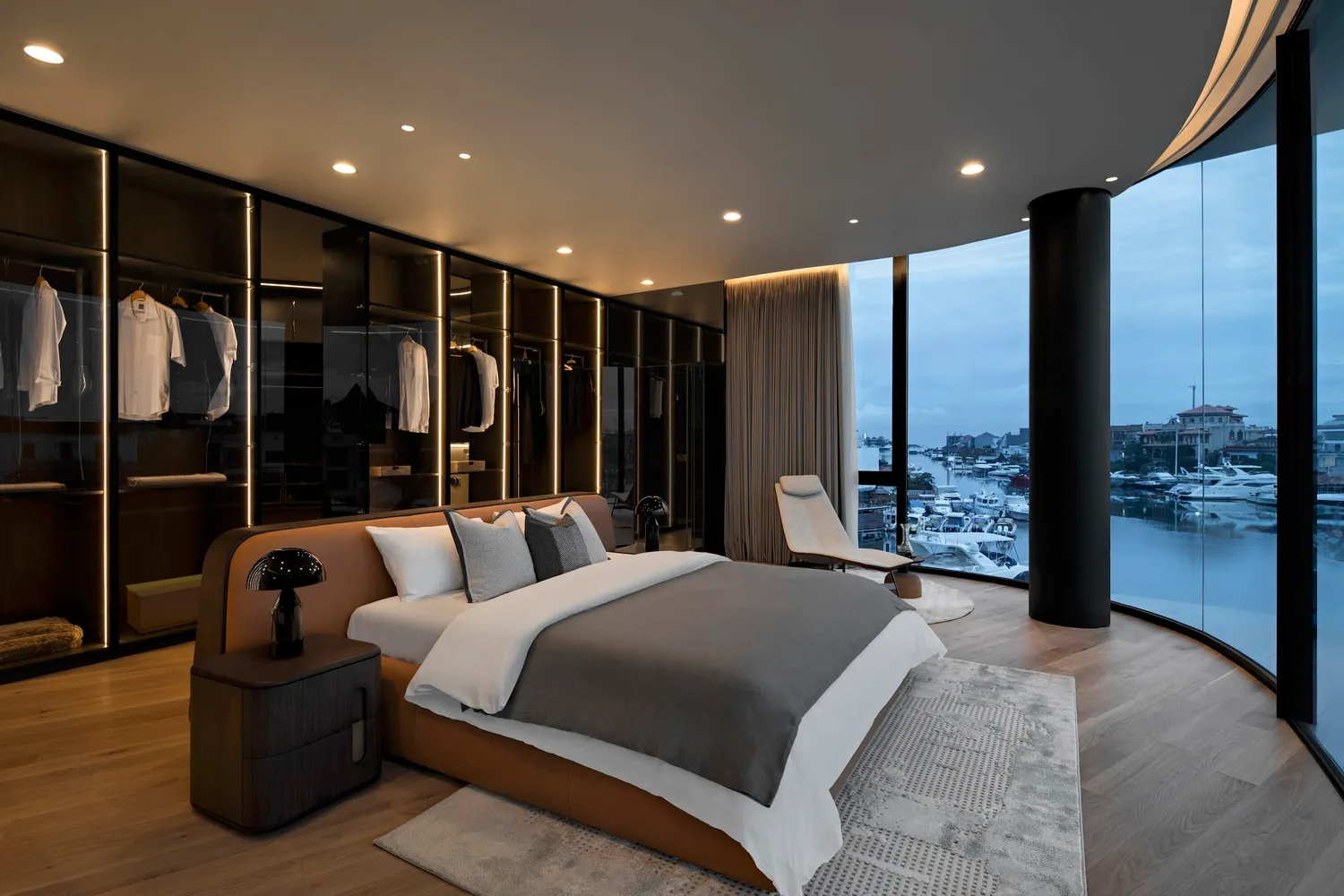 Modern bedroom with a large bed, metal headboard, glass doors, and wooden floors and furniture.