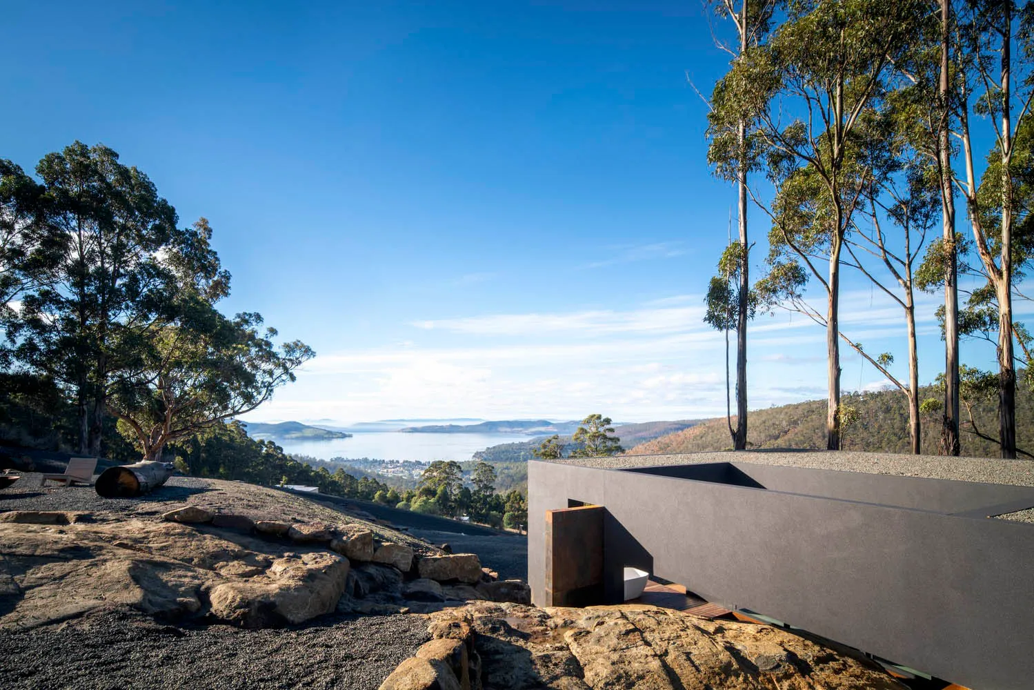 A contemporary residential exterior featuring grey stone, concrete, and metal elements.