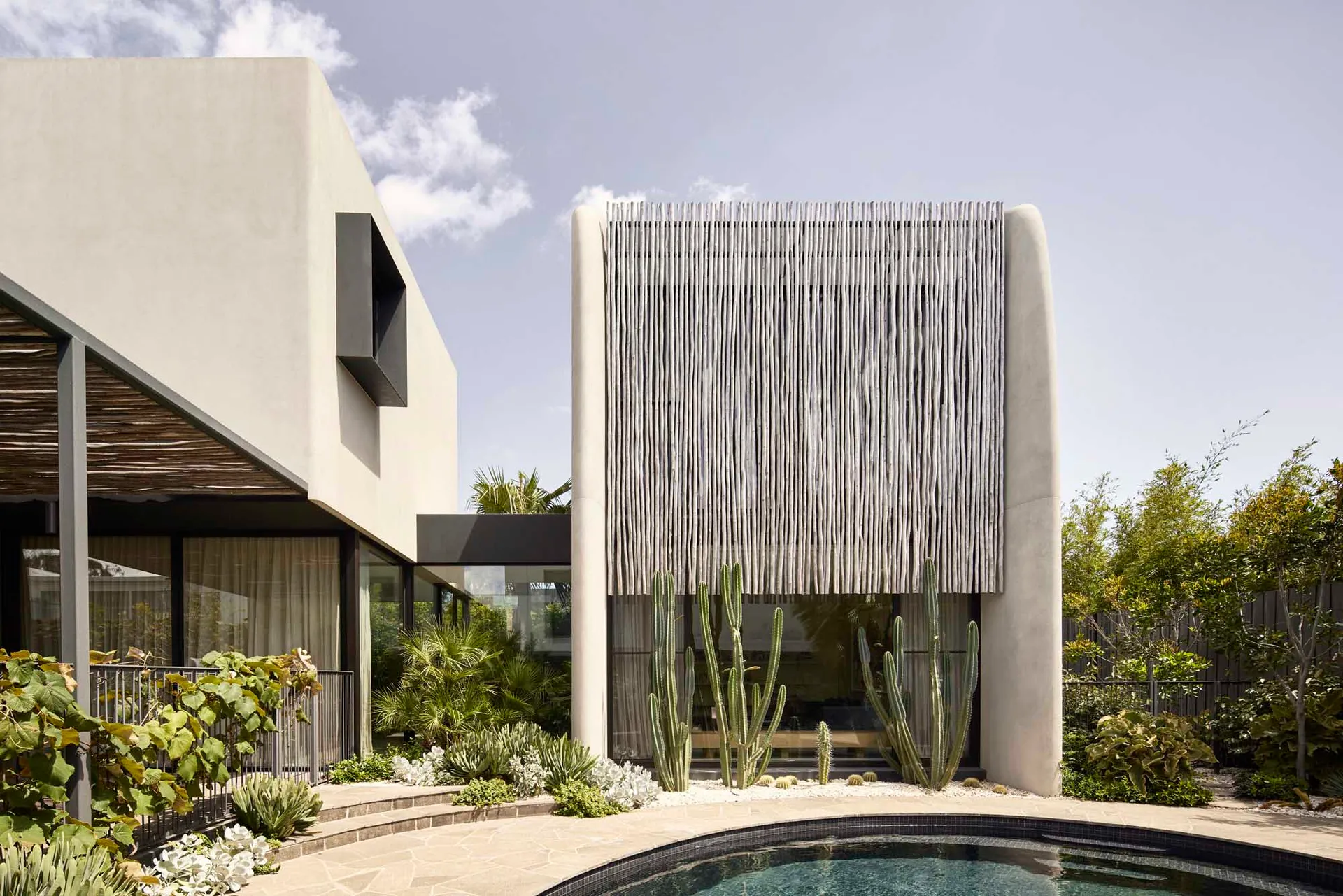 A modern concrete residence featuring cactus plants in its garden