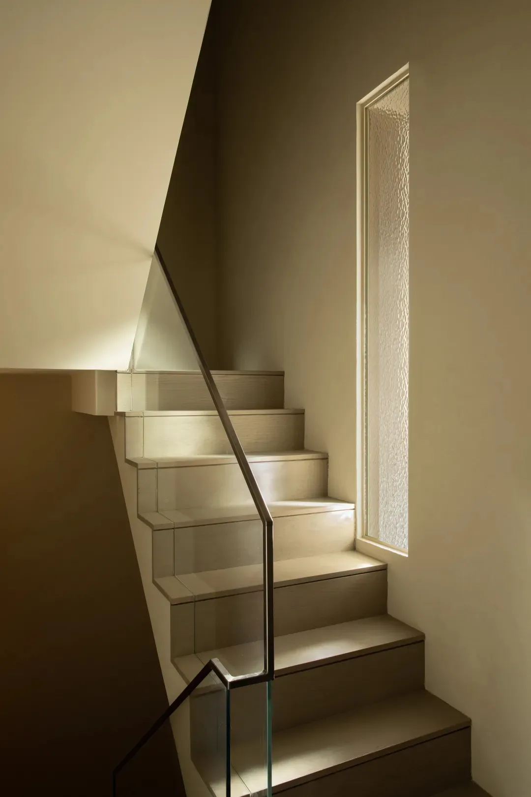 Modern minimalist staircase with glass risers and wooden treads, illuminated by ambient lighting.