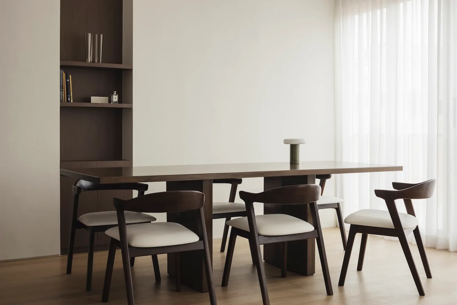 Modern dining room featuring a solid wood table and chairs, minimalistic design.