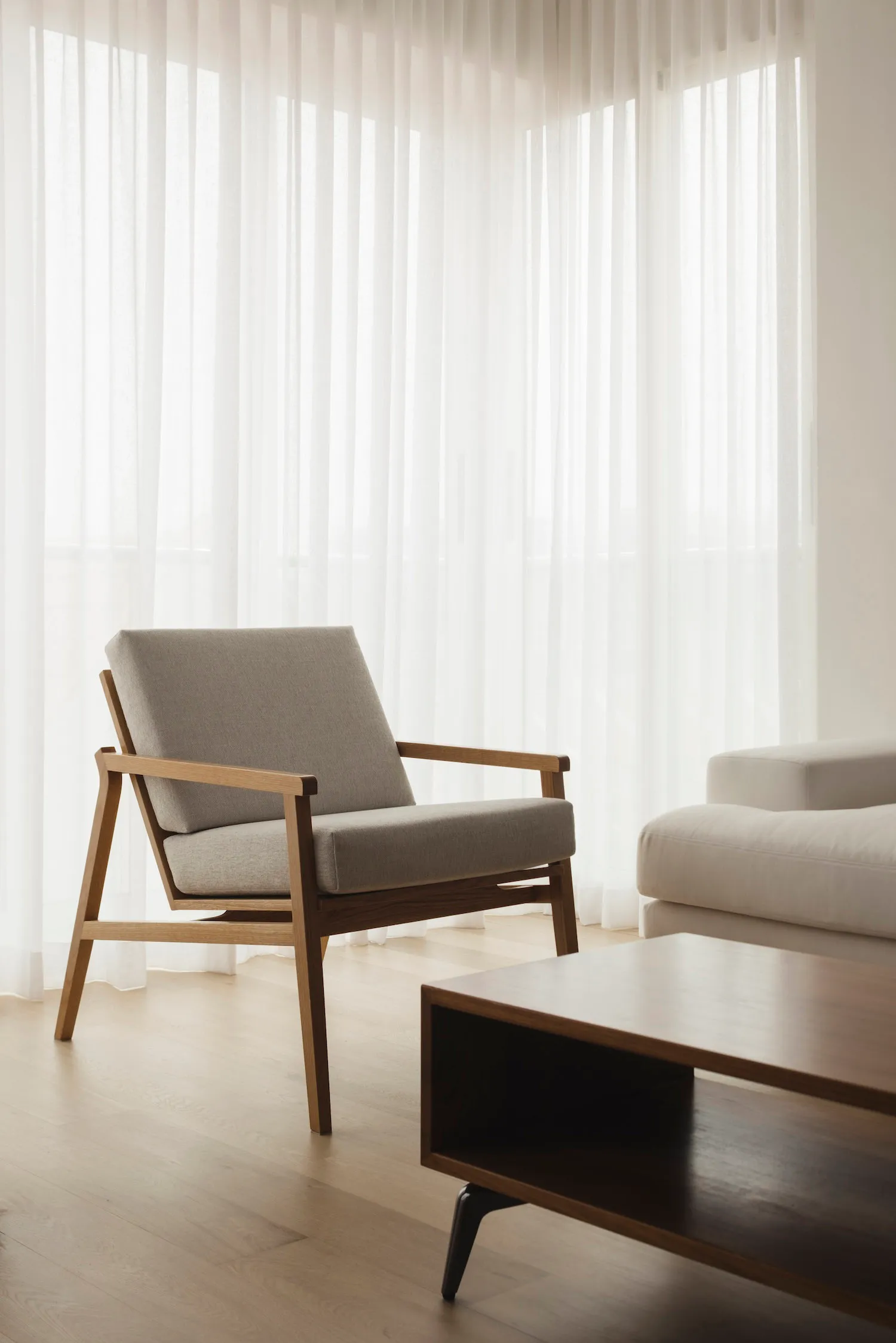 Modern living room featuring a cushioned chair with a wooden frame and light-colored fabric upholstery, alongside a wooden co