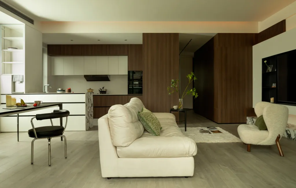A sparse, minimalist living room with a white sofa, leather armchair, and marble elements.