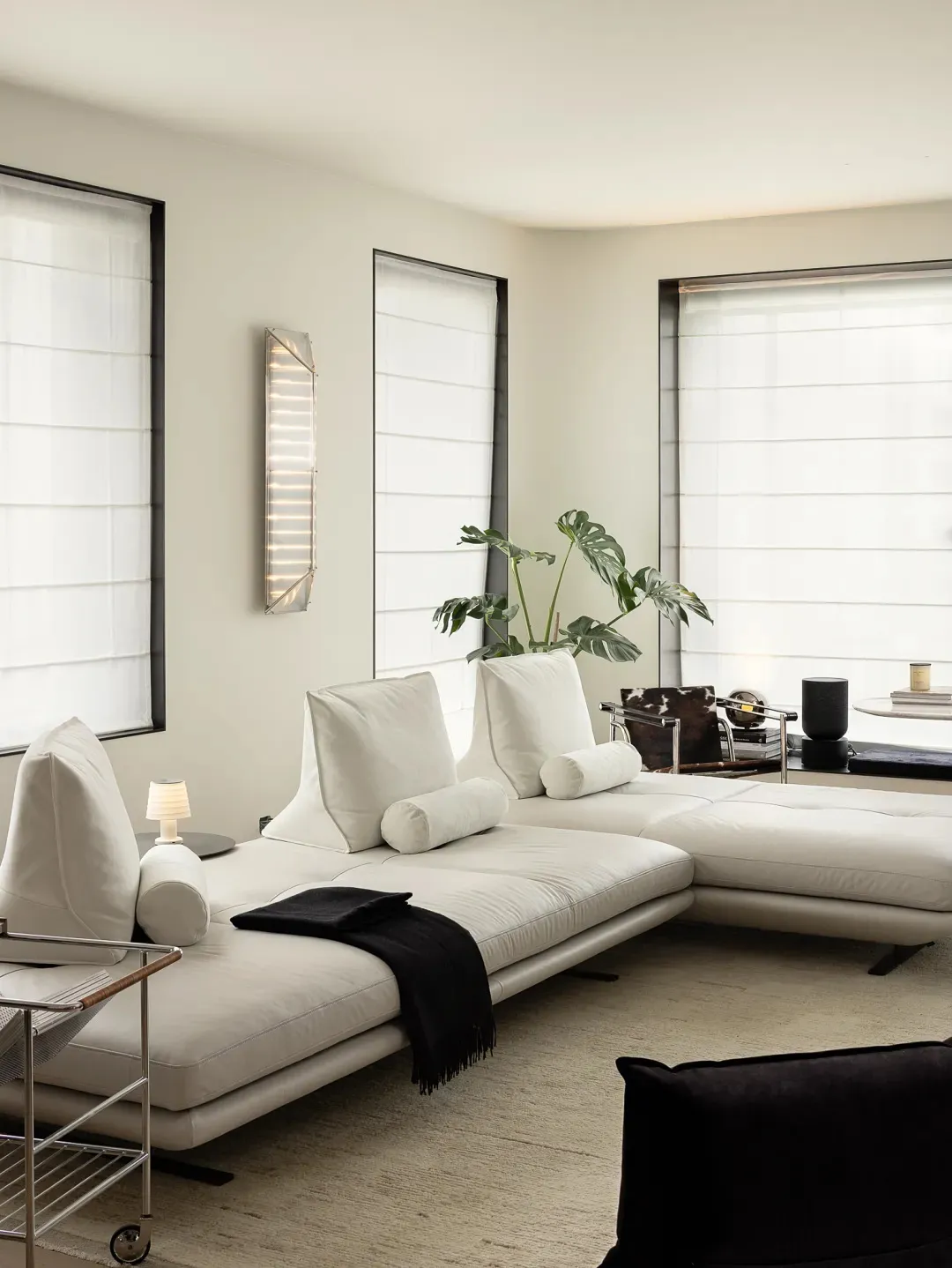 A modern white leather sofa in a living room with large windows and a minimalist design.