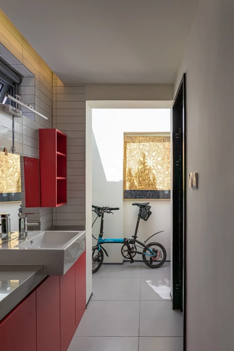A minimalist bathroom featuring red cabinetry and a bicycle hanging on the wall.