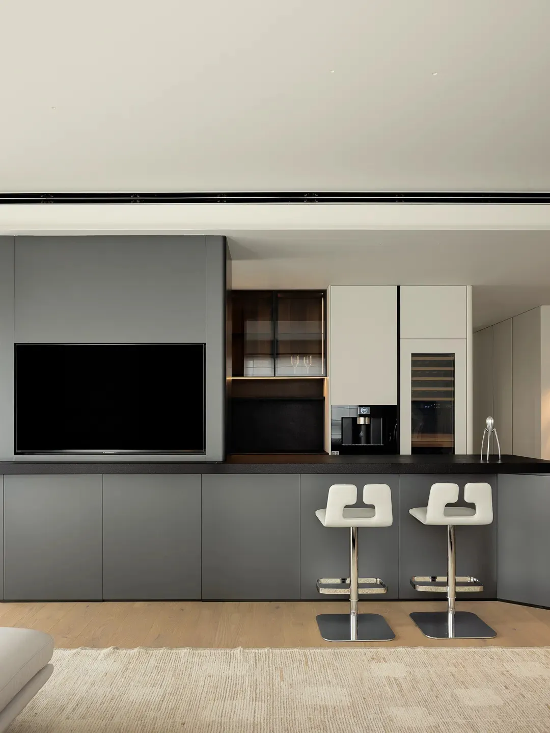 Modern residential kitchen with a bar counter, white chairs, and minimalist design.