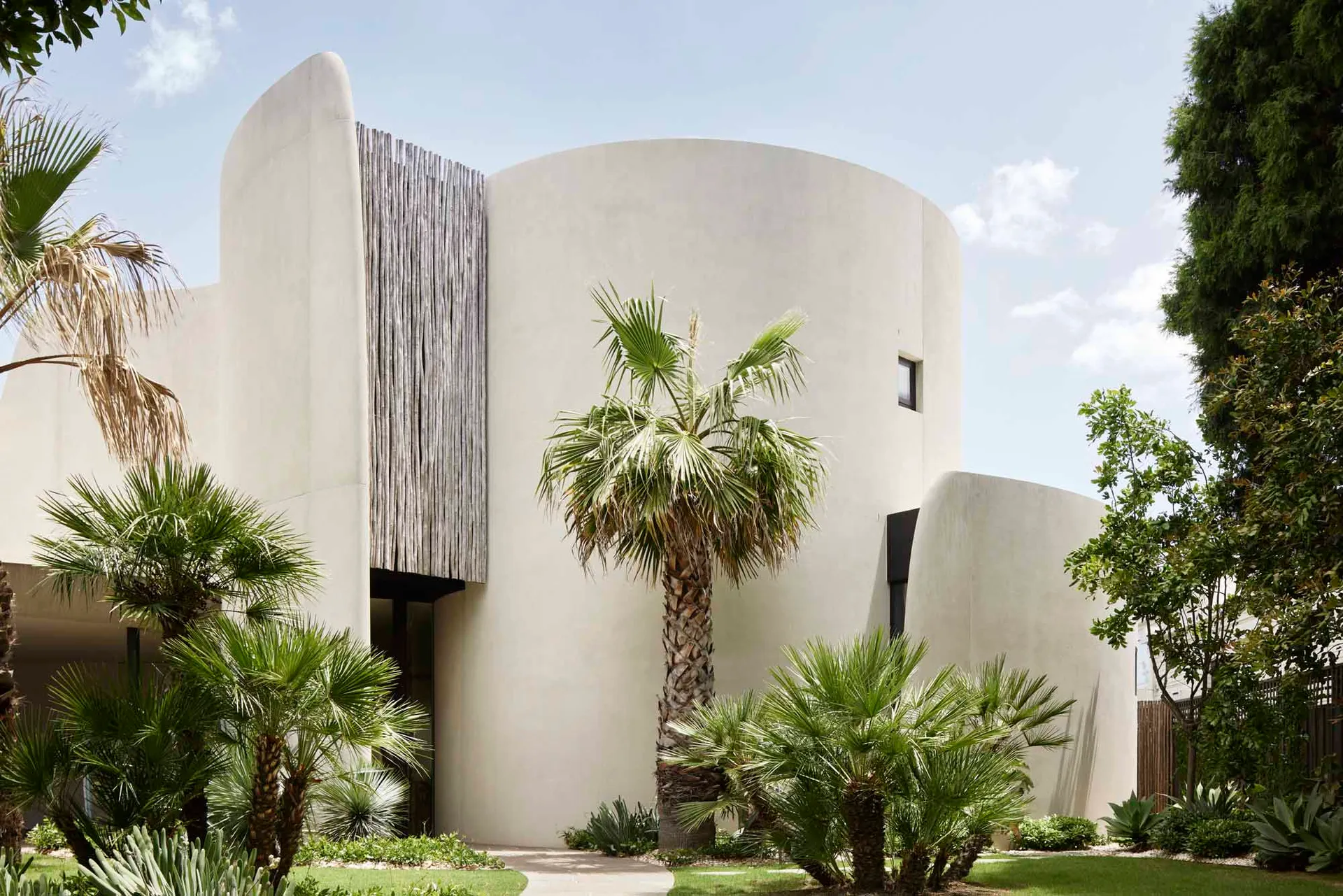 Modern building with concrete exterior and palm trees in front.