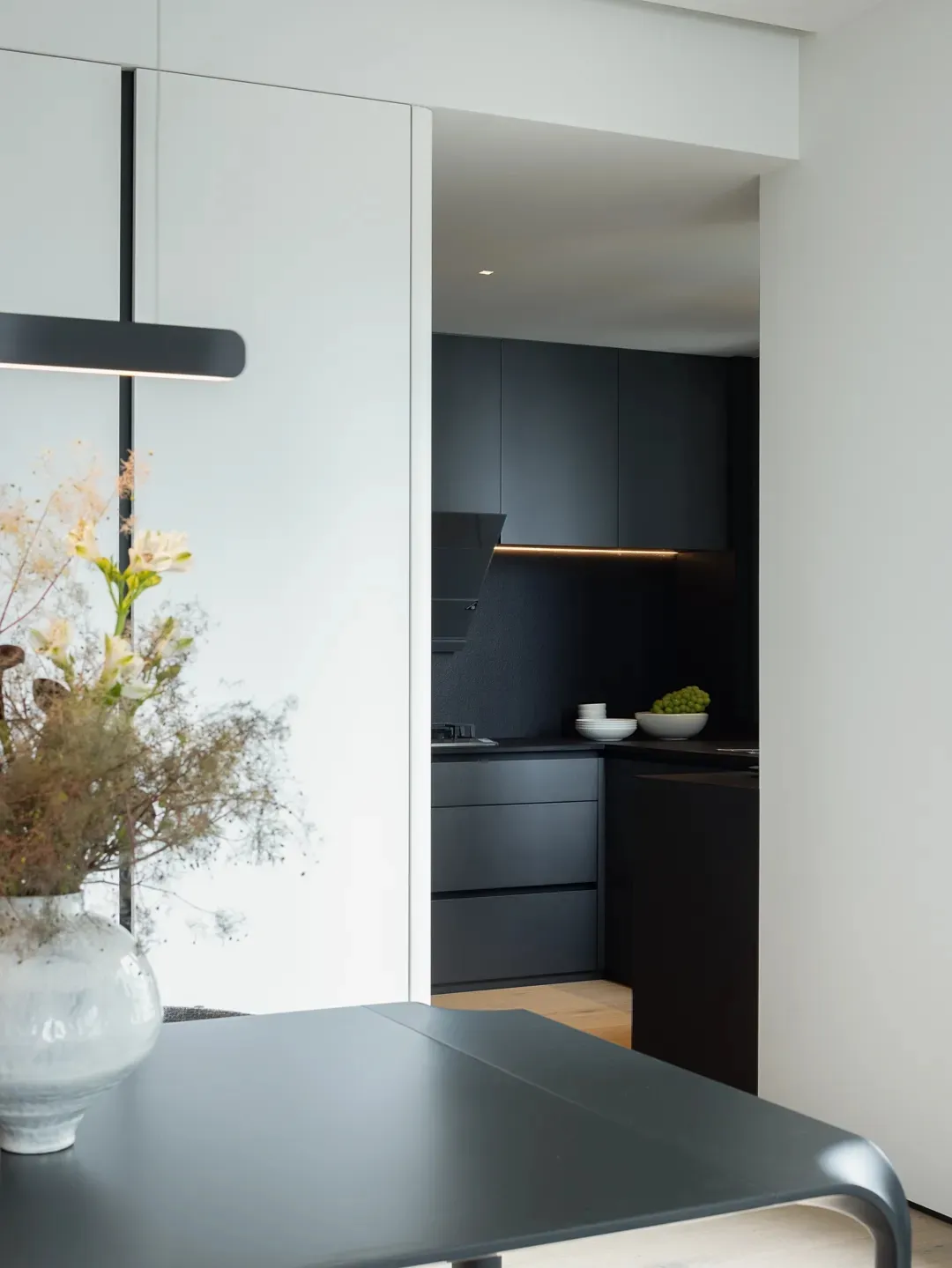 A modern minimalist kitchen with metallic surfaces, white cabinets, and a sleek design.