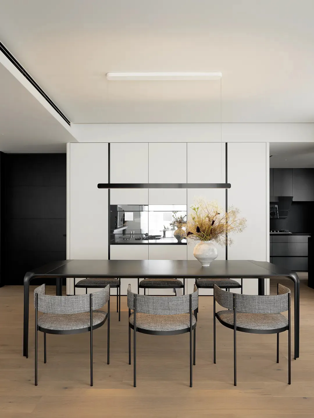Modern minimalist dining room with metal table, wood flooring, and textured fabric chairs.