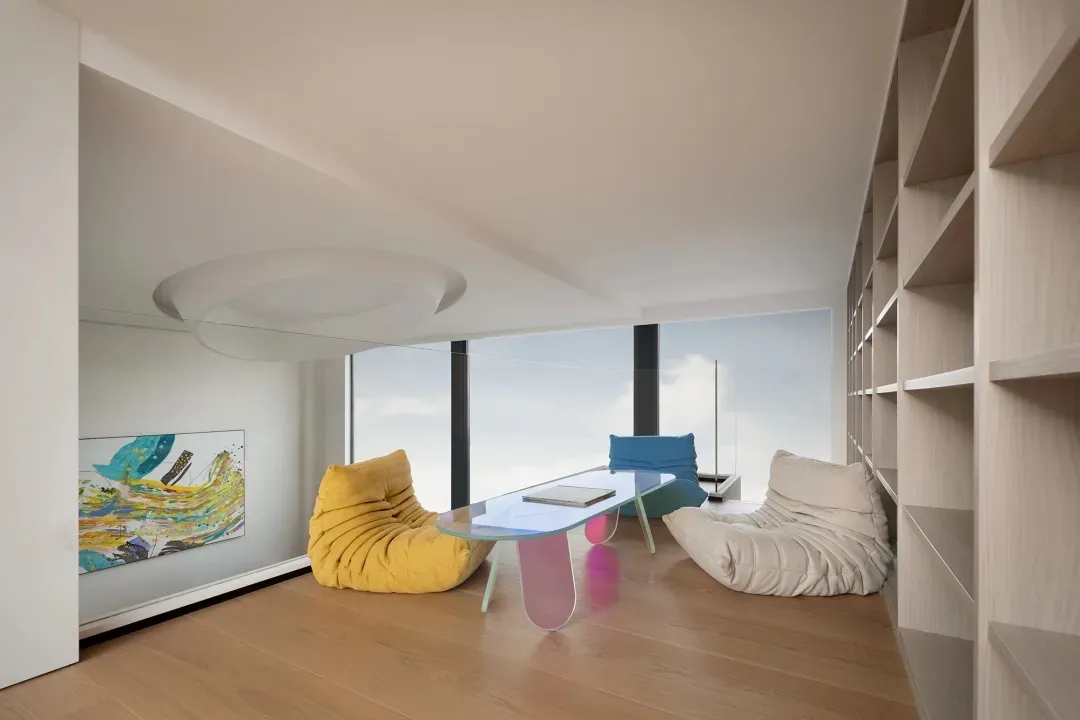 Modern living room with wood flooring, glass coffee table, and colorful sofas.