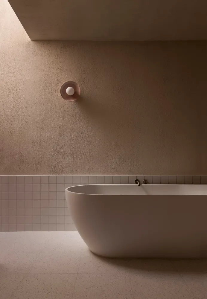 A minimalist bathroom with a freestanding bathtub and concrete tiles on the lower part of the wall.