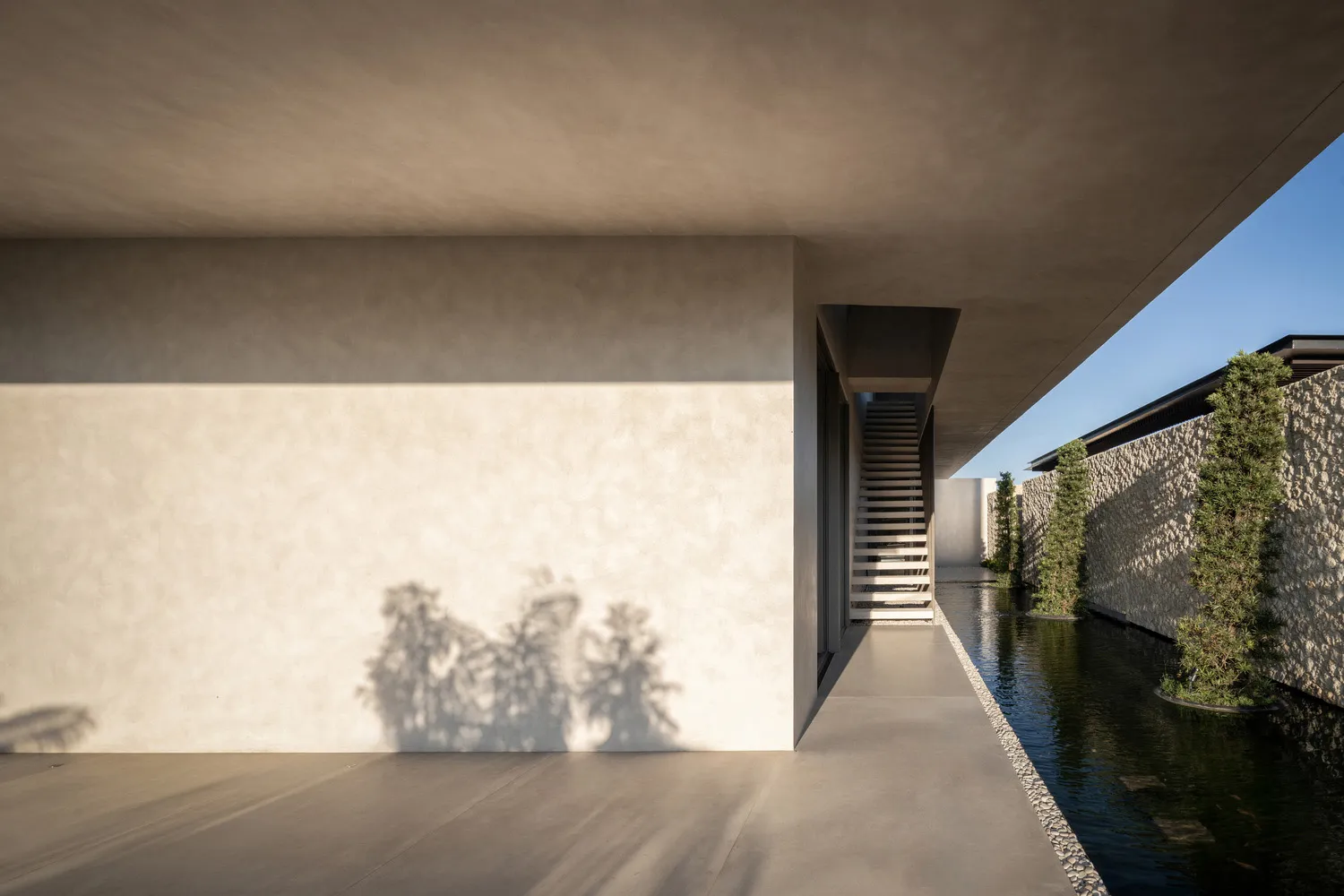 Modern minimalist interior with concrete walls and a small water feature.