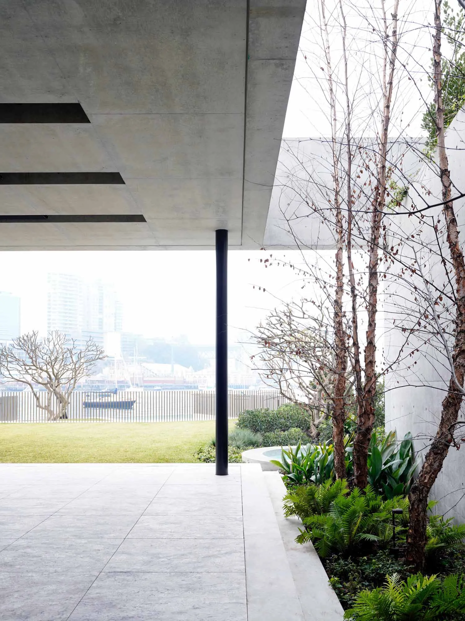 Concrete patio with greenery and trees overlooking a cityscape.