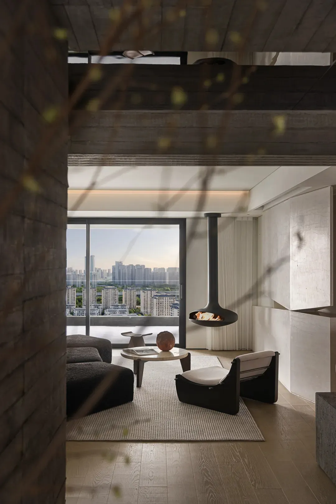 Modern concrete living room with a suspended fireplace, large windows, and minimalist furniture.