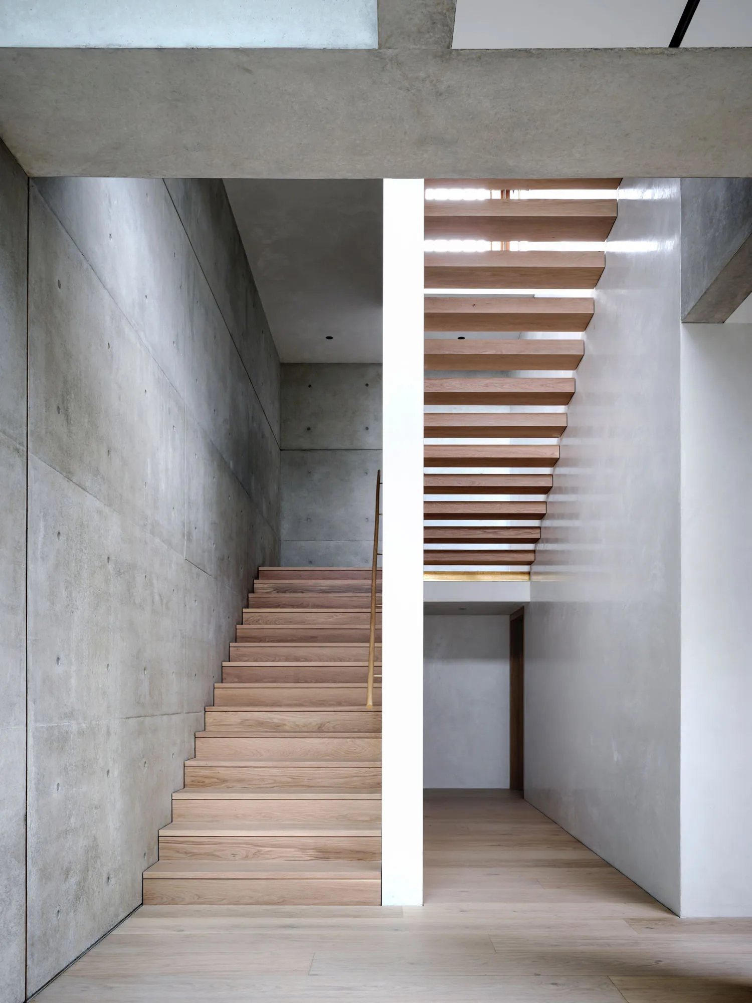 Modern, concrete staircase with wooden steps and railings, featuring a minimalist design.