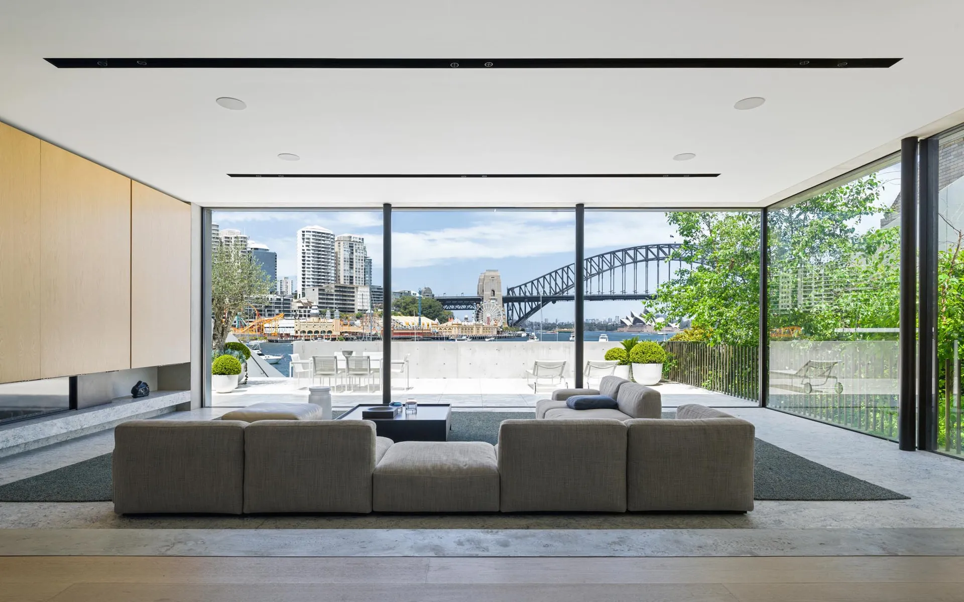 Modern living room featuring a minimalist design with large glass windows and concrete floor.