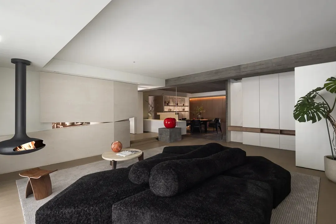A modern, minimalist living room featuring a black sectional sofa, a concrete fireplace, and a sleek, contemporary design.