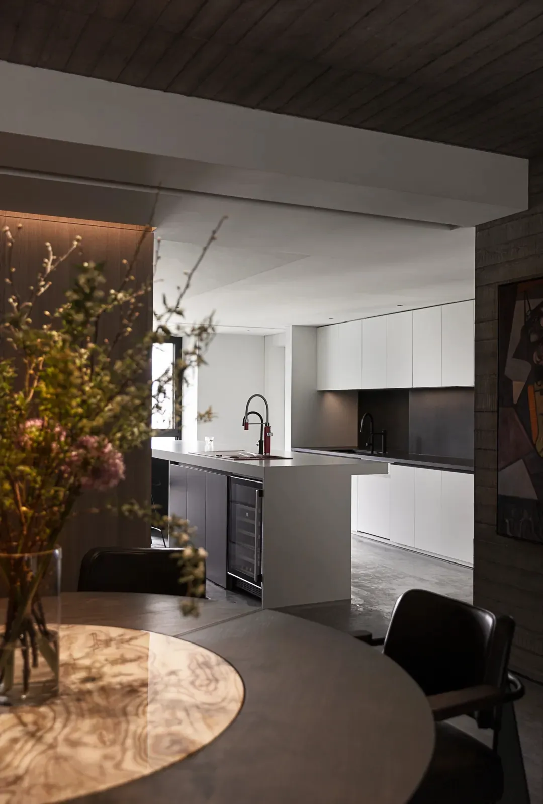 A modern kitchen with white cabinets, stainless steel appliances, and a wooden ceiling.