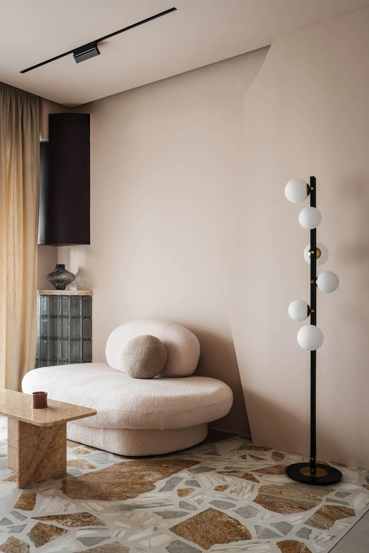 A stylish living room with a plush, rounded sofa and a geometric, terrazzo-patterned floor.