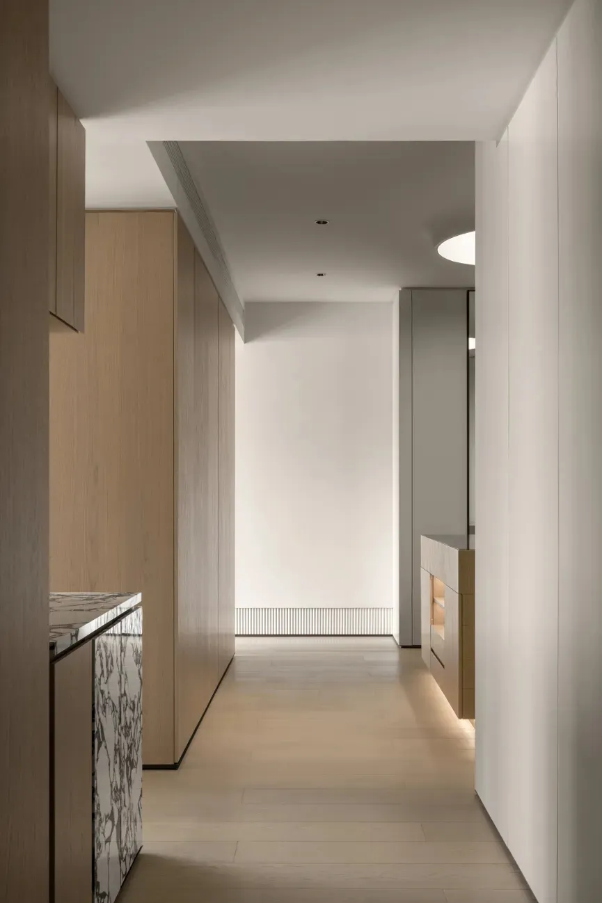 A modern kitchen features white marble countertops with wooden cabinets.