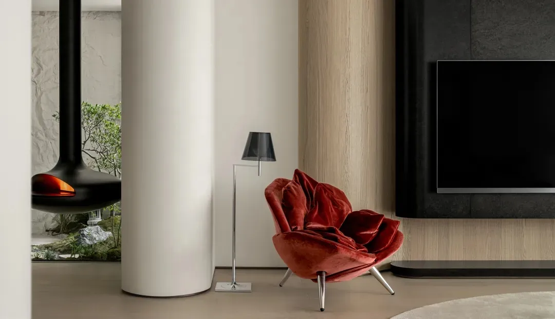 A modern living room featuring a red velvet chair, wooden column, and carpet.