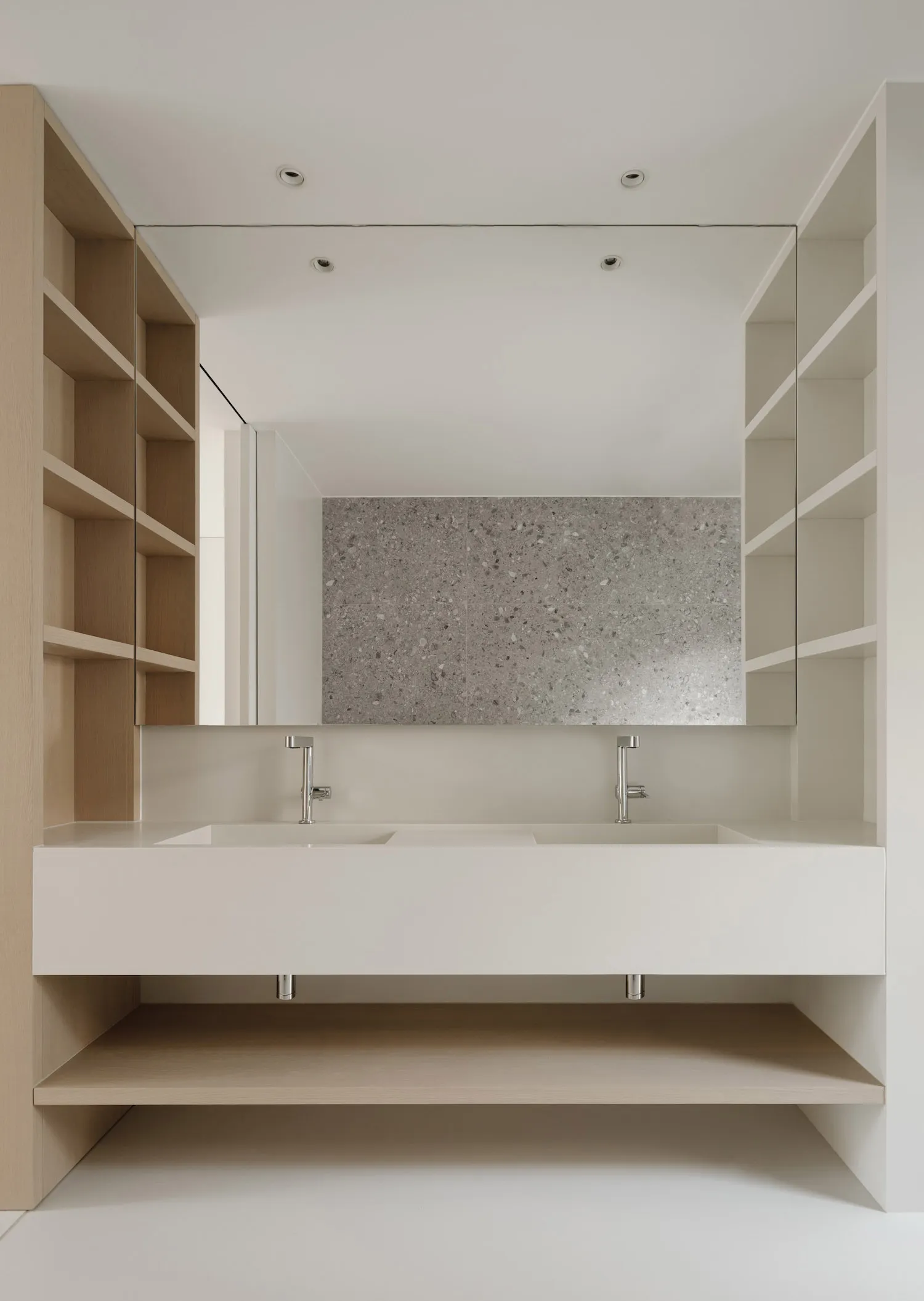 A minimalist modern bathroom with a white floating vanity, concrete countertop, and large mirror.