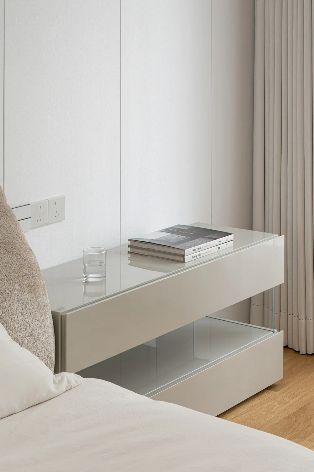 Minimalist bedroom featuring a glass nightstand with a glass top and a shelf.