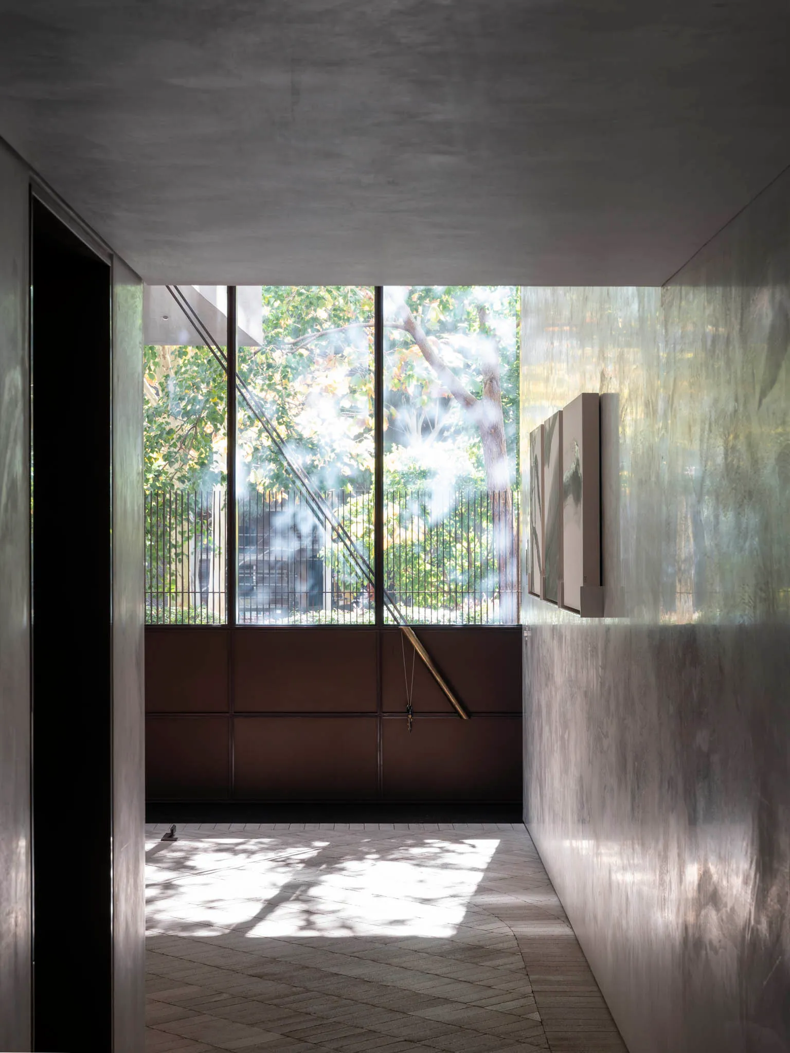 A modern interior space with concrete walls and a large window showcasing an outdoor view with trees.