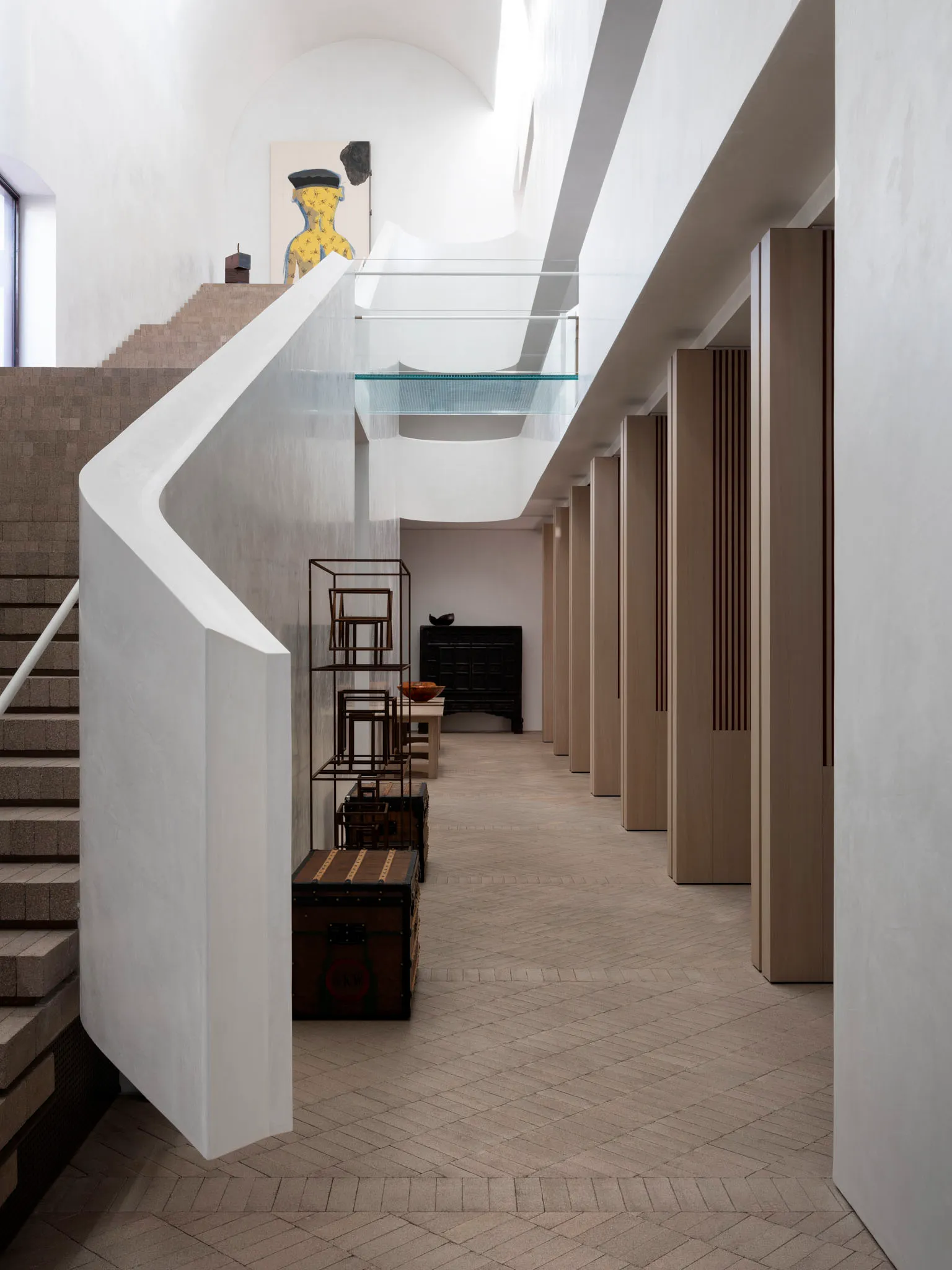Modern interior of a building featuring concrete walls, glass windows, and brick flooring.