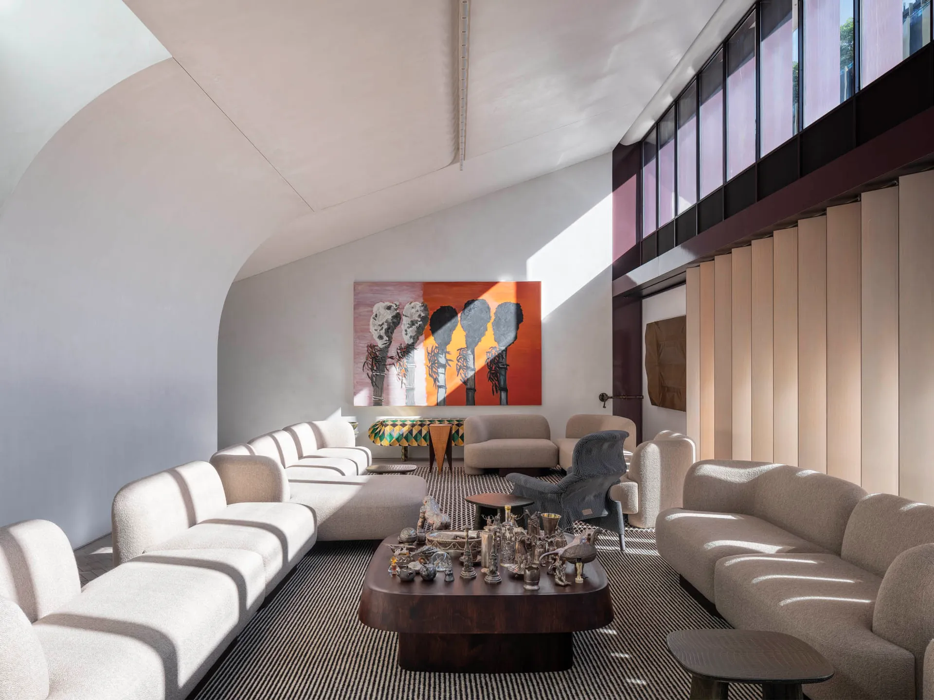 A modern living room with textured fabric sofas and concrete flooring, featuring abstract art and a dark wooden coffee table.