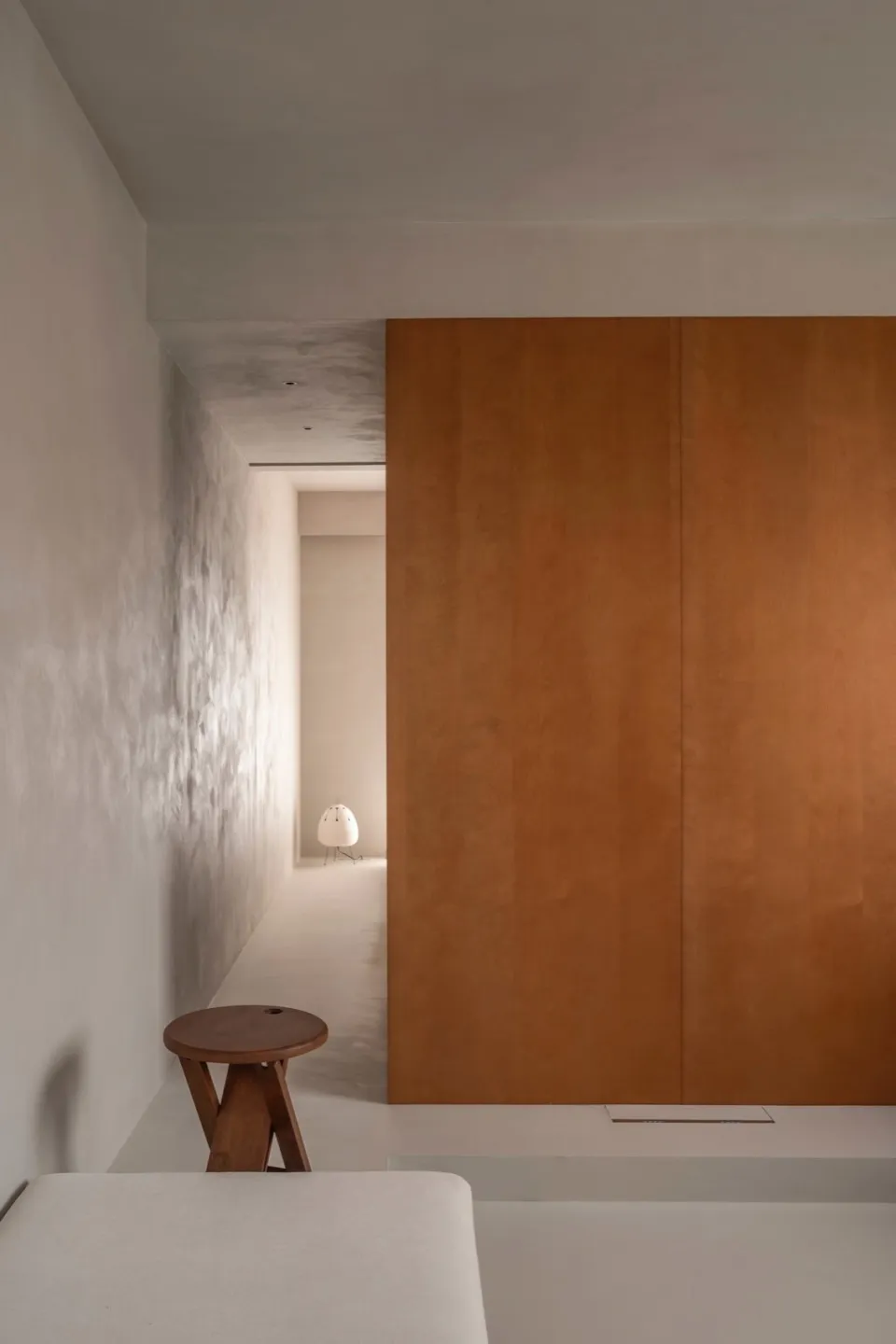 A minimalist interior space with a wooden wall and concrete flooring.