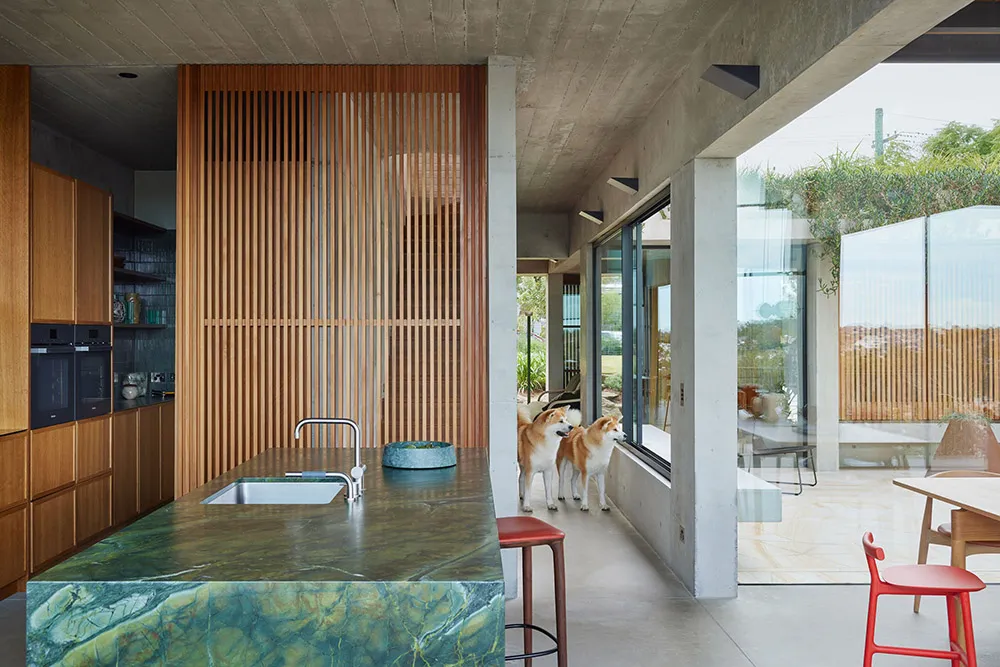 Modern kitchen with green-marble countertop and wooden slatted wall.
