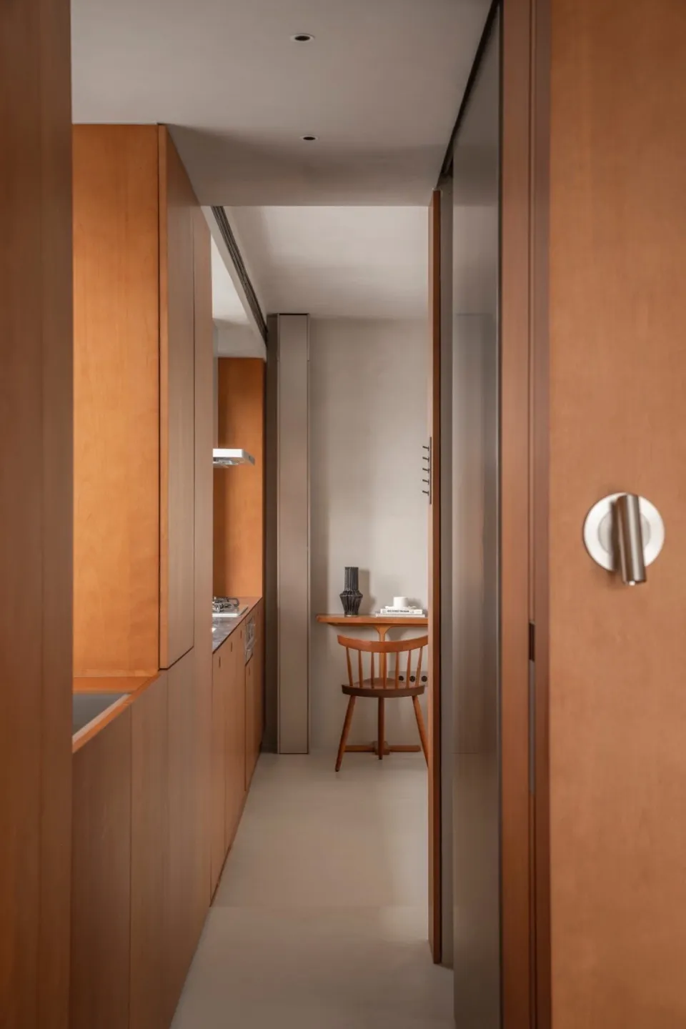 A modern kitchen with wooden cabinets, concrete floor, and a small dining area.
