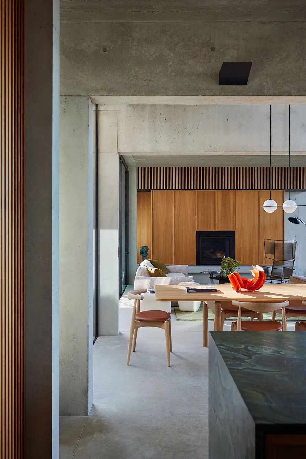 A modern living room featuring concrete and wood elements, including a fireplace and seating area.