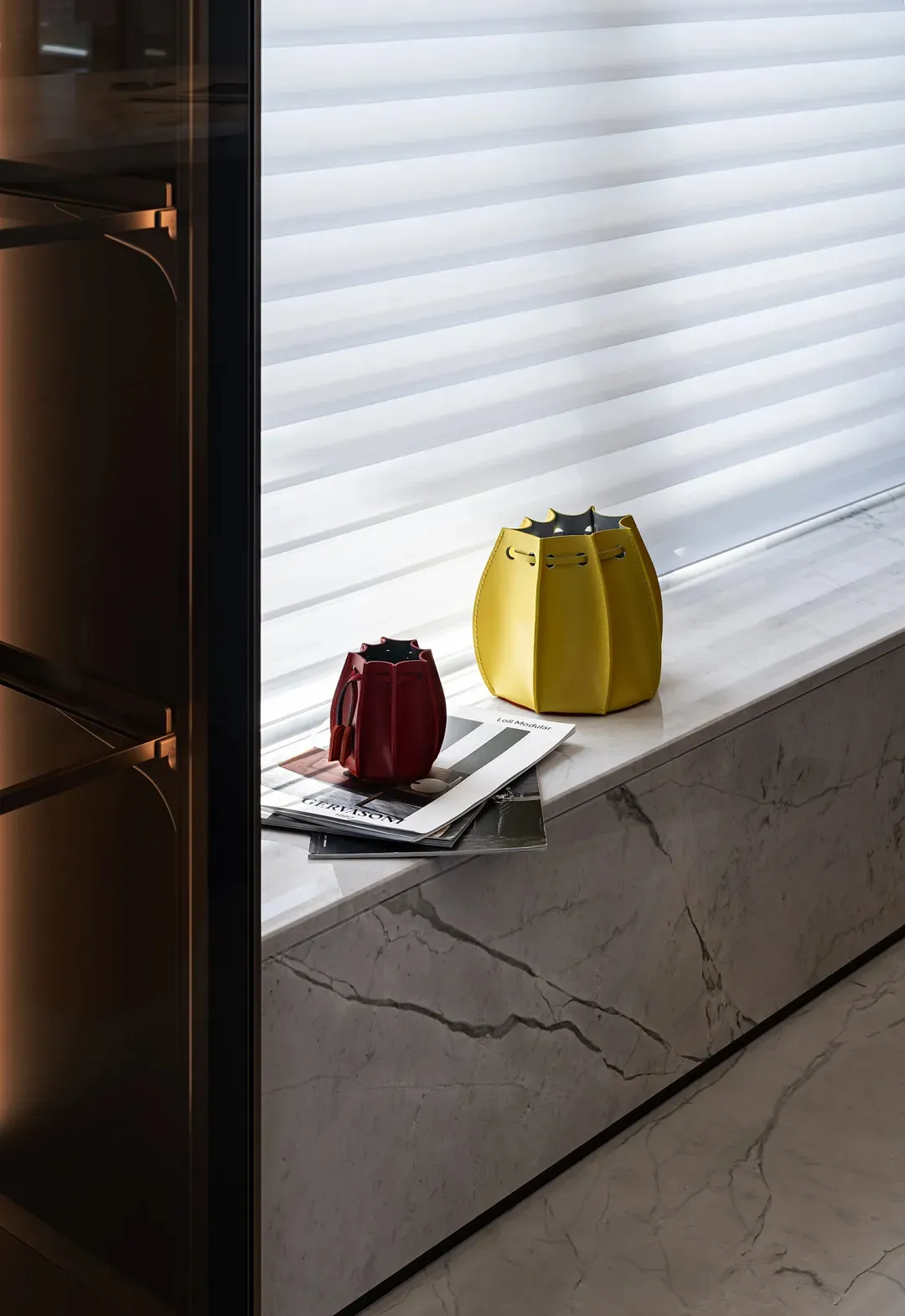 Modern console with marble top and leather bag on a marble ledge.