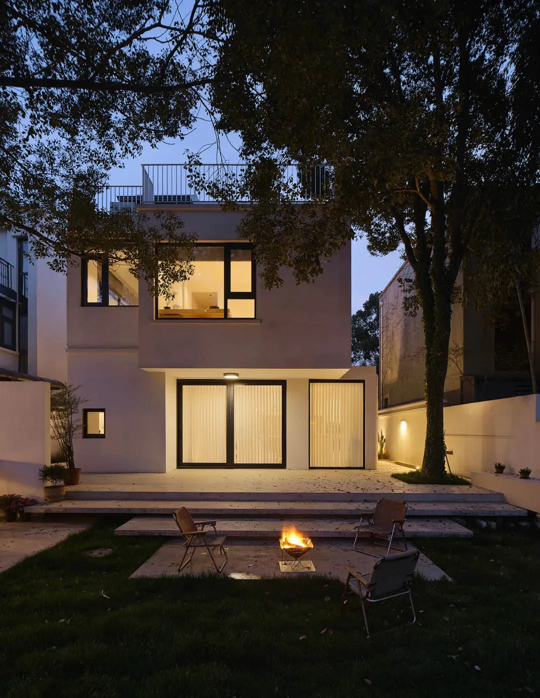 A modern house exterior with a fire pit in a backyard