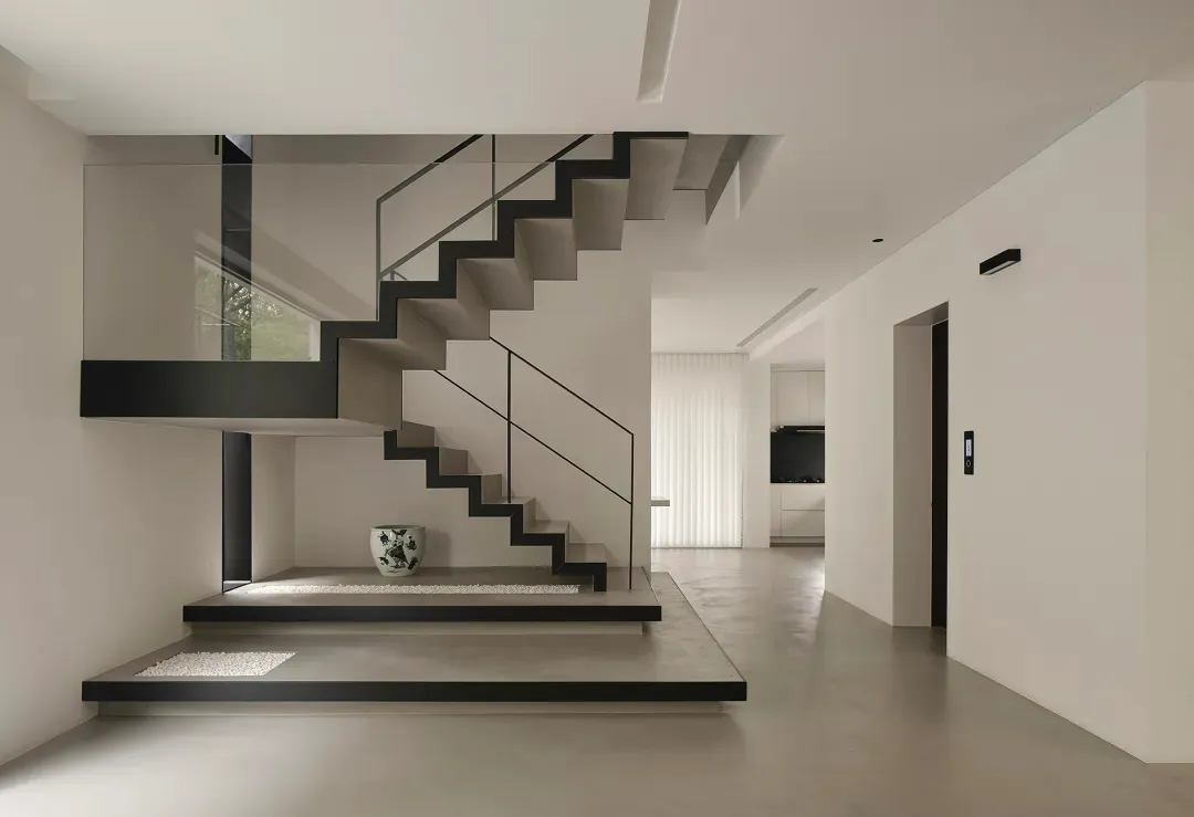 A modern minimalist interior with concrete and glass features. The space showcases clean lines, natural light, and a seamless