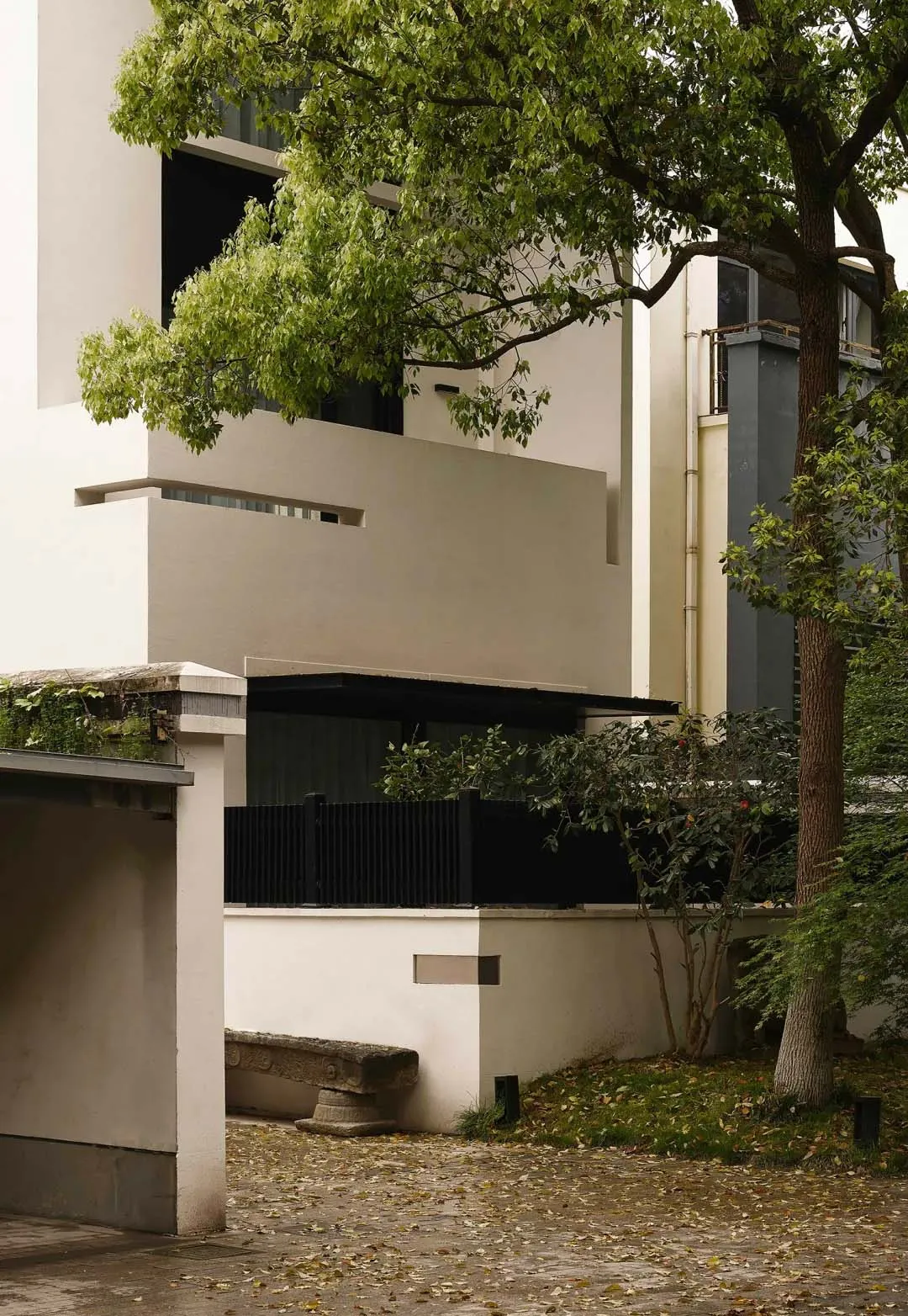Modern minimalist building with concrete exterior and greenery.