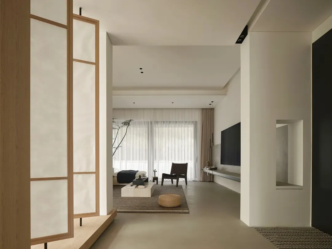 A minimalist living room featuring concrete furniture, wooden accents, and fabric textiles.