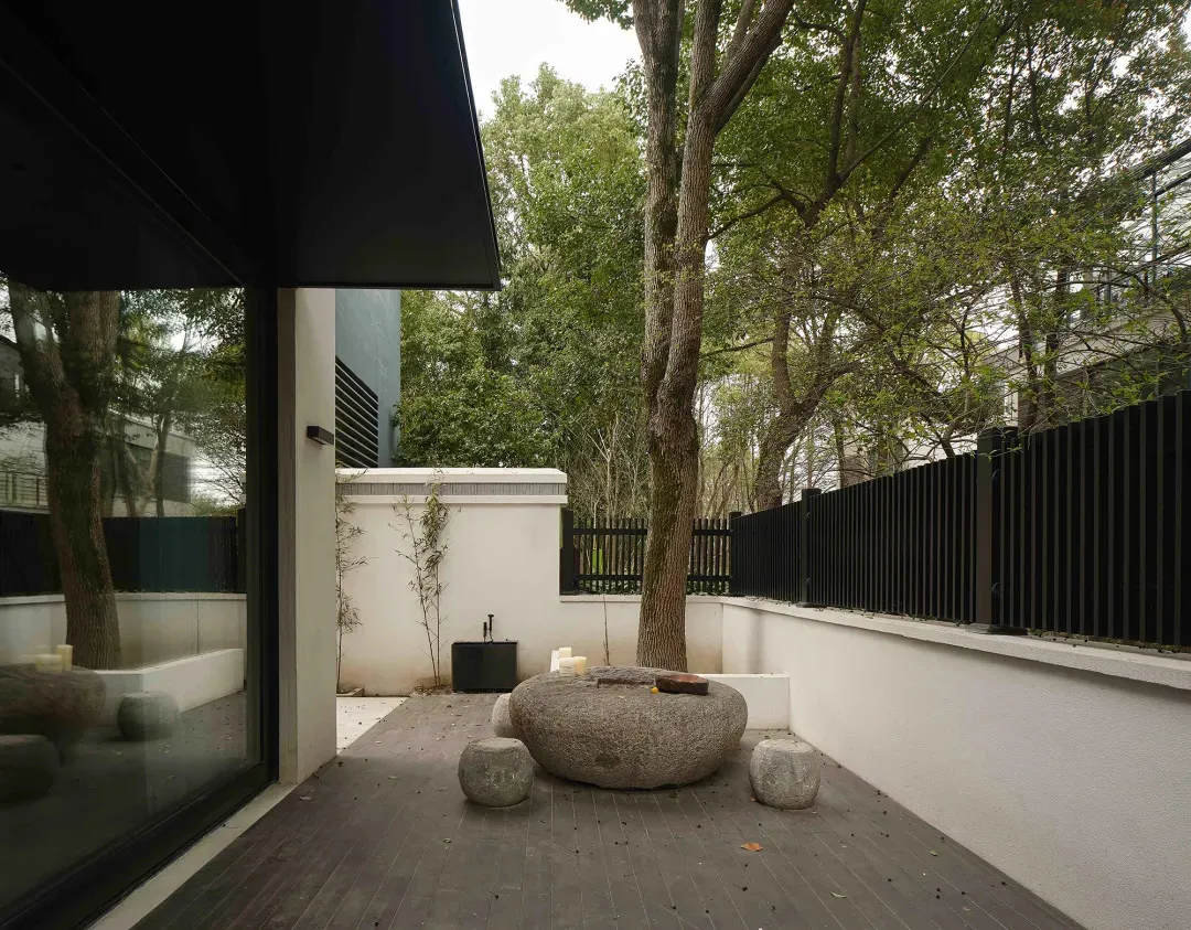 A minimalist terrace garden featuring stone elements and a large stone table with stools.