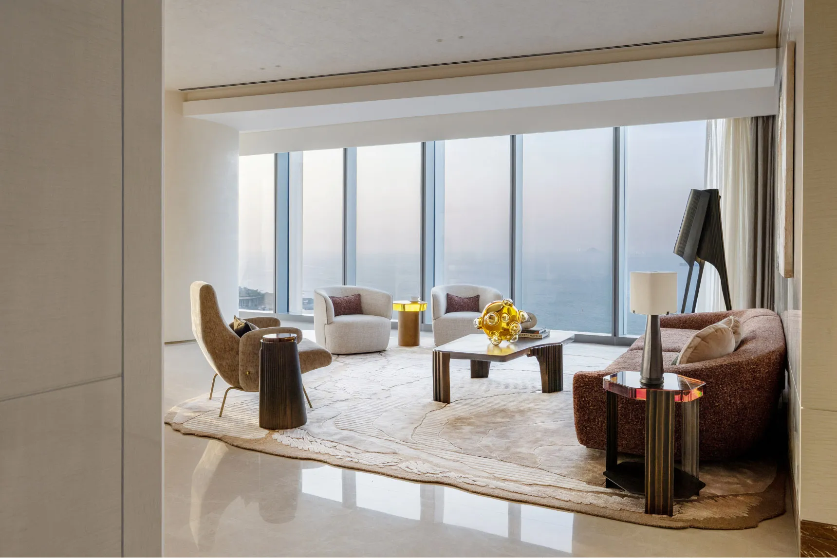 Modern living room with minimalist design featuring a marble floor and panoramic ocean view through floor-to-ceiling windows.