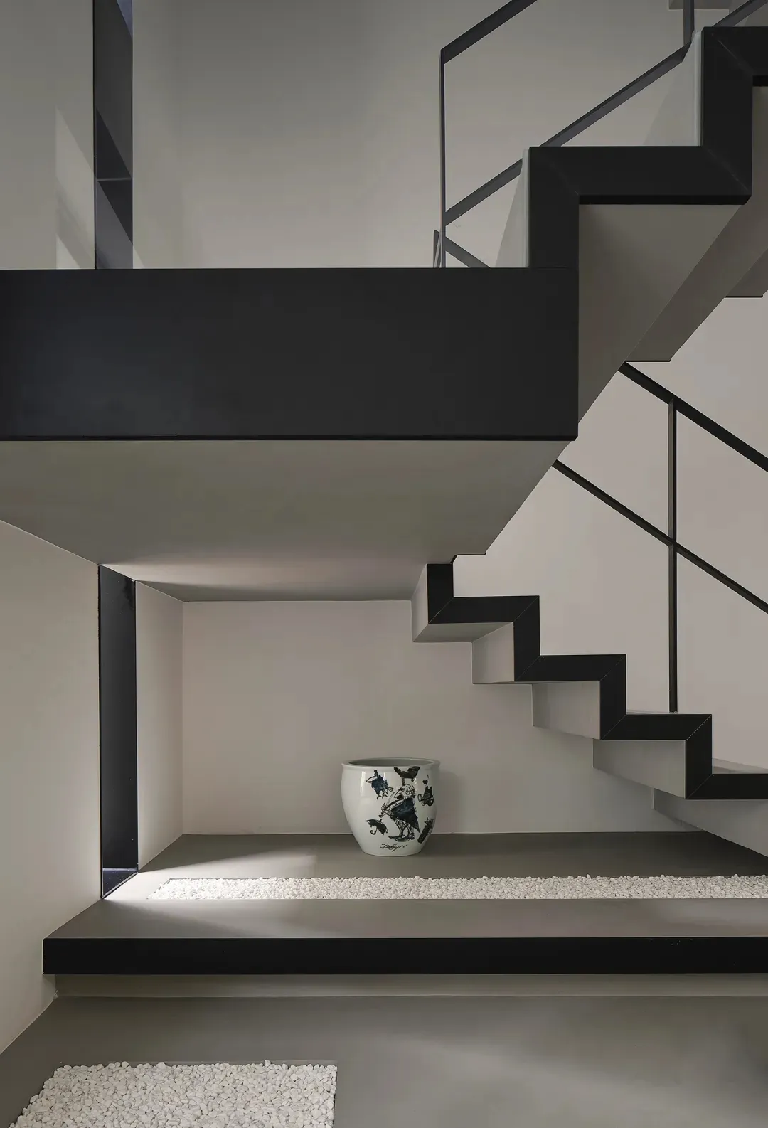 Modern concrete staircase with black metal railings and white ceramic pot.