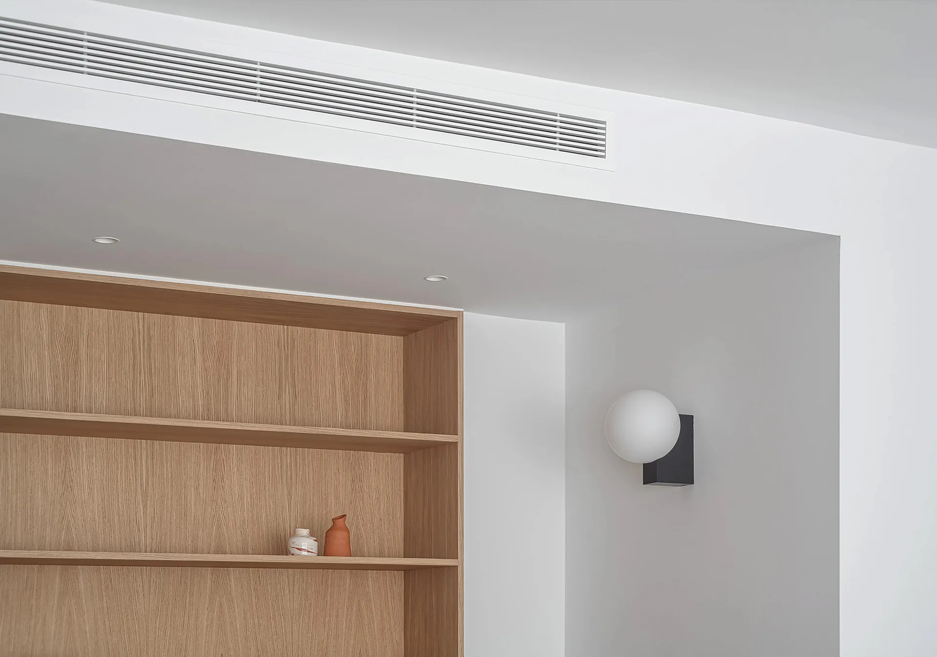 A minimalist bookshelf with a wooden finish, featuring a sleek design and a few decorative items.
