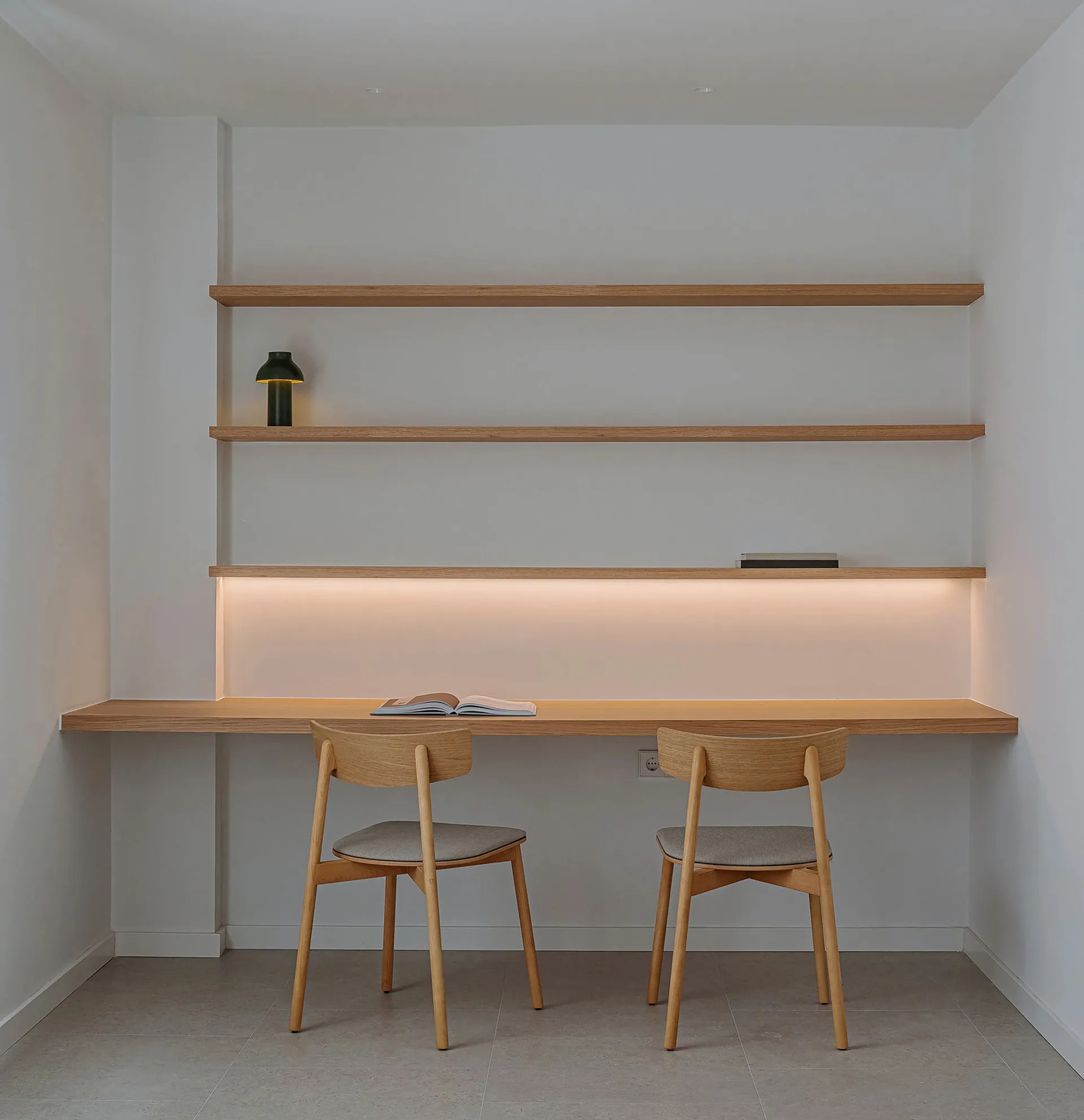 A minimalist workspace with a wooden desk and shelves.