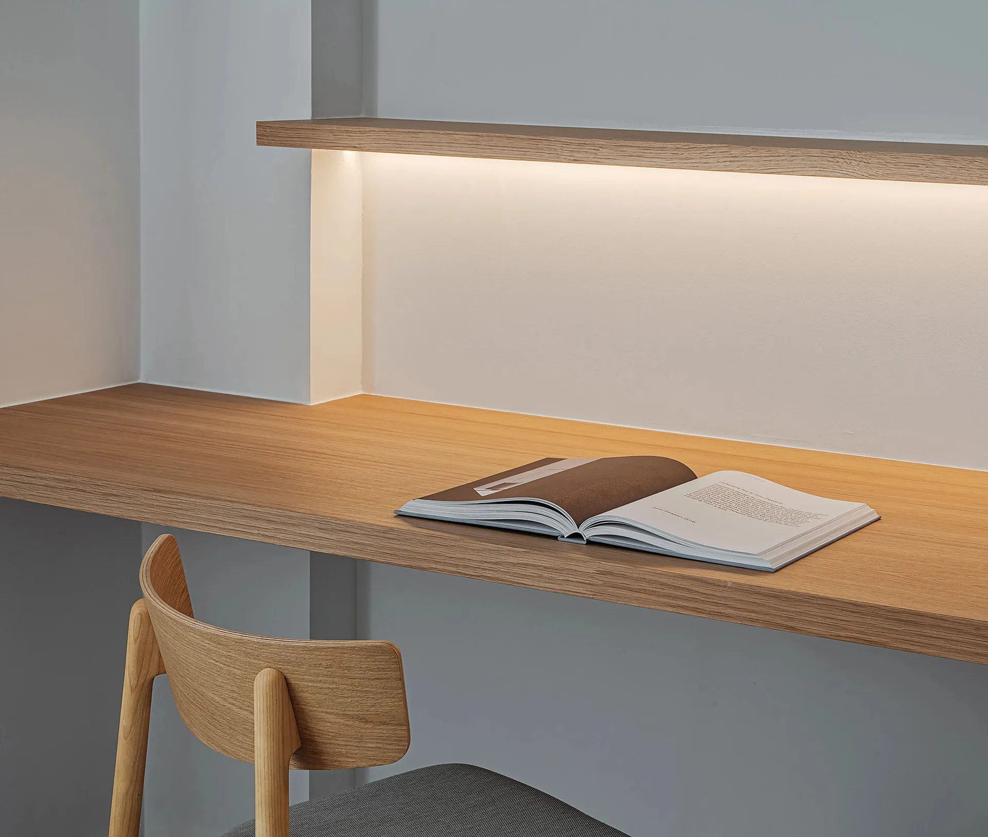 An open book on a modern, floating desk with ambient lighting in a minimalist home office setting.