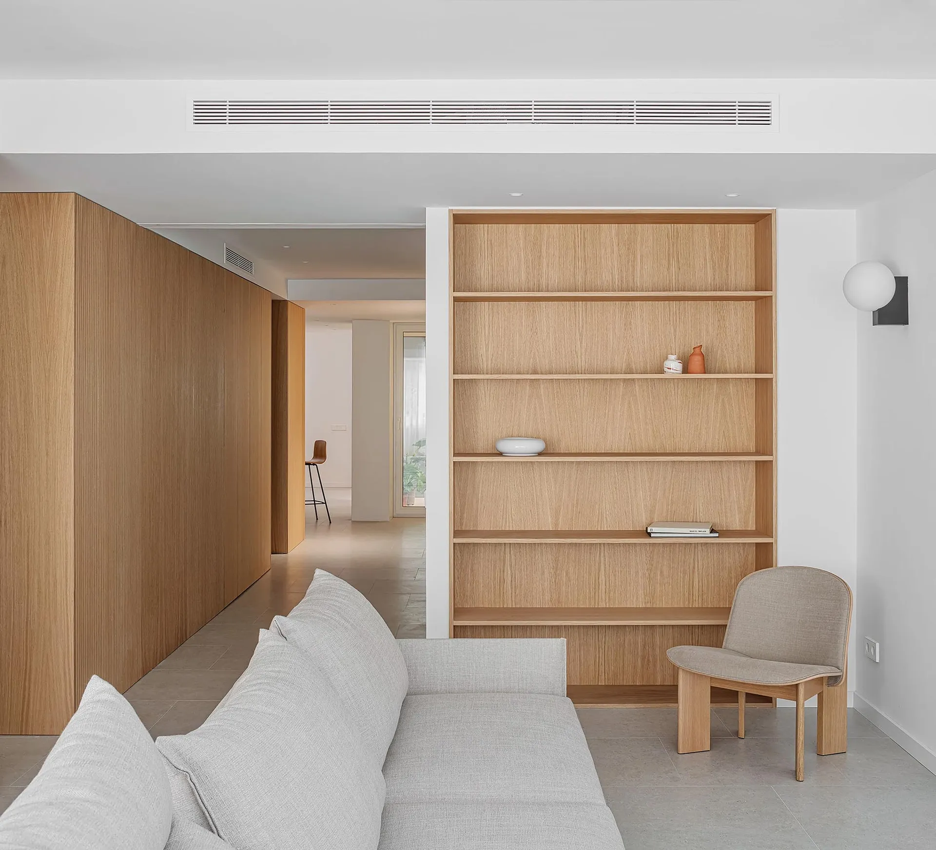 A modern minimalist living room featuring wooden shelves and a comfortable couch.