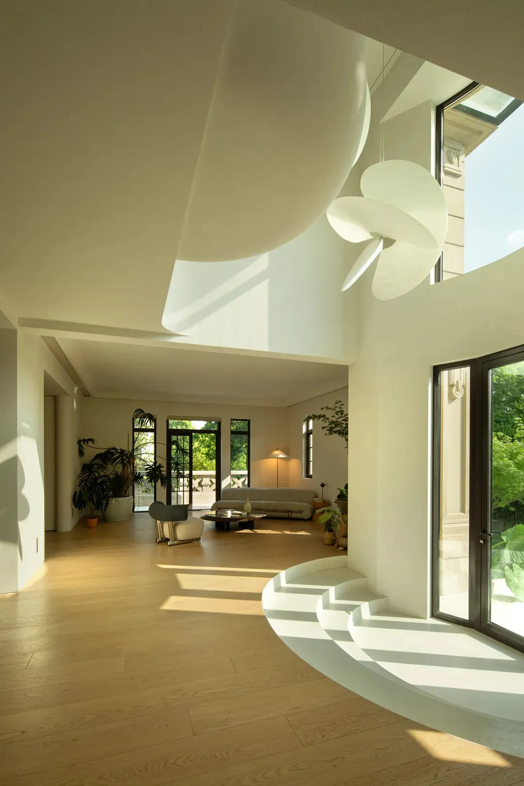 A modern minimalist living room with white walls and wooden flooring, featuring a cozy sofa, chairs, and a coffee table.