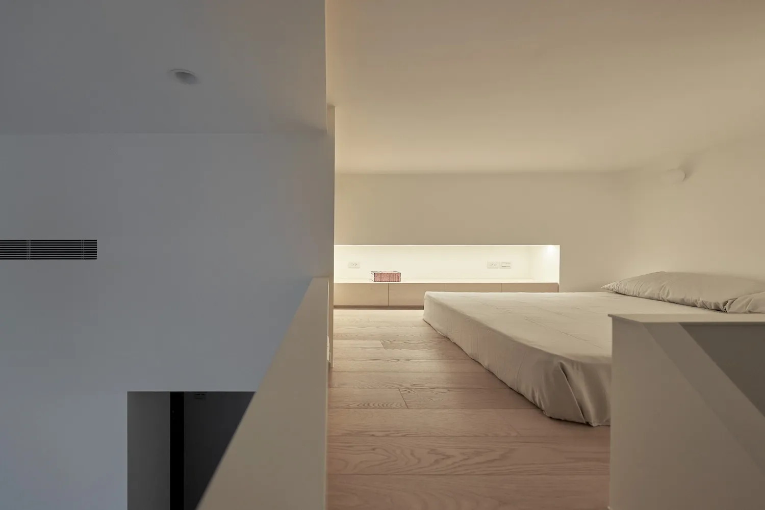 A minimalist bedroom featuring a wood floor and a bed with a minimalist design.