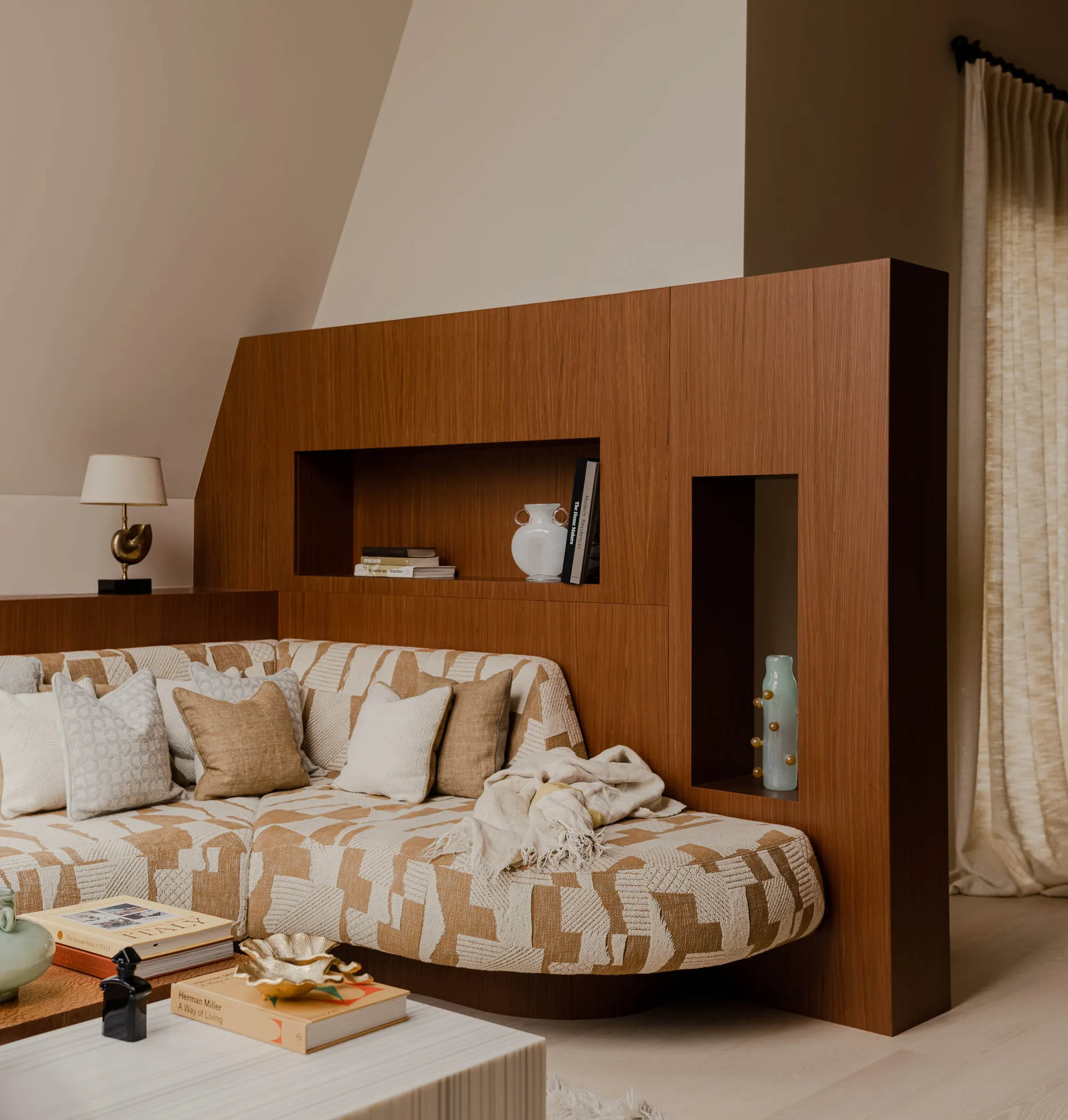 A modern interior living room with a wooden panel wall featuring built-in shelves and a patterned sofa.