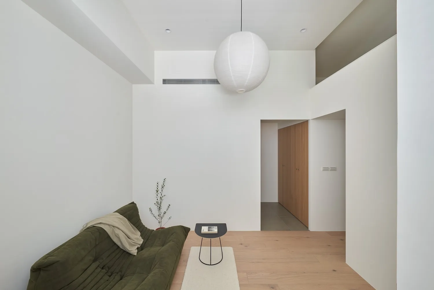 Modern living room featuring a wooden floor, minimalist furniture, and soft lighting.